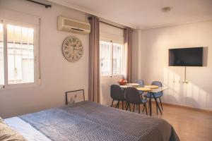 1 dormitorio con cama, mesa y reloj en Aparthotel Costa Blanca, en Torrevieja