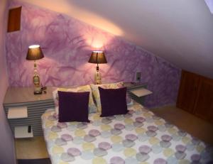 a purple bedroom with a bed with two lamps at Apartamento El Desván in Pedraza-Segovia