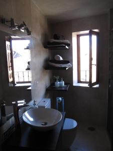 a bathroom with a sink and a toilet and two windows at Apartamento El Desván in Pedraza-Segovia