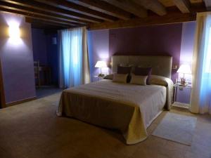 a bedroom with a large bed with purple walls at La casa de Don in Pedraza-Segovia