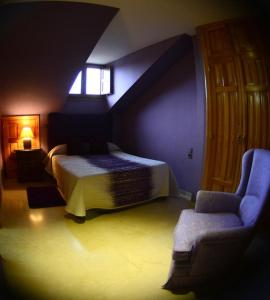 1 dormitorio con 1 cama, 1 silla y 1 ventana en Apartamento El Desván, en Pedraza-Segovia