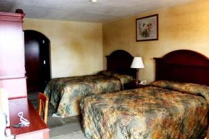 a hotel room with two beds and a lamp at Summit Inn Hempstead in Hempstead