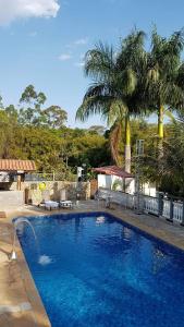 une grande piscine bleue dans une cour avec des palmiers dans l'établissement Belo Recanto, à São José dos Campos