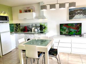 a kitchen with a table with chairs and a tv at Barcaresa-Agréable appartement vue mer panoramique in Le Barcarès