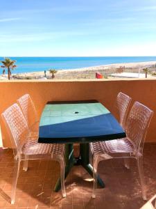 een blauwe tafel en stoelen op een balkon met uitzicht op het strand bij Barcaresa-Agréable appartement vue mer panoramique in Le Barcarès
