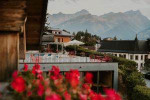 a view of a building with red flowers in the foreground at Les Mazots du Clos in Villars-sur-Ollon