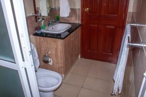 een badkamer met een wit toilet en een wastafel bij Kasty T Apartments- W Place in Nairobi +24 foto's