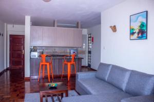 salon z kanapą i 2 pomarańczowymi krzesłami w obiekcie Kasty T Apartments- W Place w mieście Nairobi