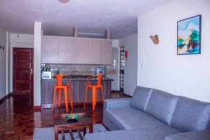 een woonkamer met een bank en 2 oranje stoelen bij Kasty T Apartments- W Place in Nairobi