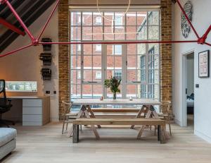 een kamer met een houten tafel en een groot raam bij ALTIDO Stylish 1-bed loft apartment near Battersea Park, South London in Londen