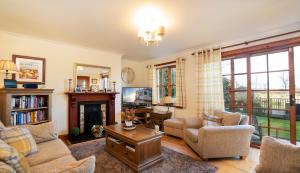 een woonkamer met meubilair en een open haard bij Osborne Steading in St Andrews