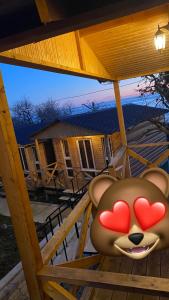 a teddy bear with hearts on its face sitting on a porch at Guest house Adel in Novy Afon