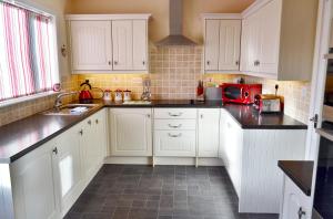 een keuken met witte kasten en zwarte aanrechtbladen bij Osborne Cottage in Southend