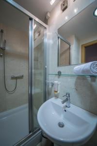 a bathroom with a sink and a shower and a mirror at Putnik Inn Belgrade in Belgrade
