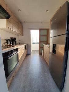 una cocina con nevera de acero inoxidable y armarios de madera en Appartement calme, chaleureux et lumineux en Douai