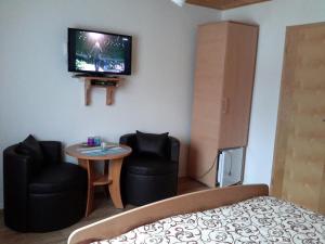 a bedroom with a bed and two chairs and a tv at Lake House 1 in Plitvička Jezera