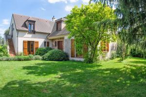 une maison avec un arbre dans la cour dans l'établissement Les Prunelliers, à Rambouillet