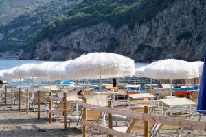 eine Gruppe von Stühlen und Sonnenschirmen am Strand in der Unterkunft Hotel Oriente in Vico Equense