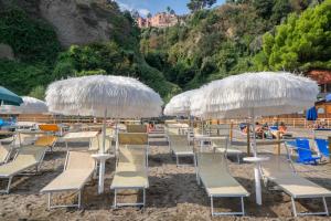 a beach area with chairs, tables and umbrellas at Hotel Oriente in Vico Equense