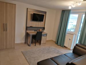 a living room with a couch and a desk with a television at Hotel im Gässle in Süßen