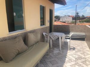 ein Sofa auf einem Balkon mit einem Tisch und Stühlen in der Unterkunft Casa na Praia de Barra do Gil in Vera Cruz de Itaparica