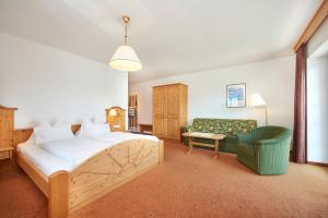 a bedroom with a bed and a green chair at Hotel Stadler am Attersee in Unterach am Attersee