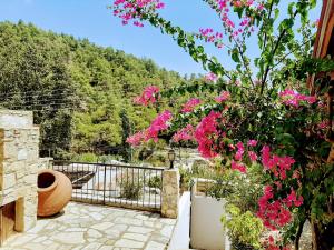 un jardín con flores rosas y una valla en Blue Cottage, en Apsiou