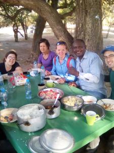 a group of people sitting around a table with food at Naumba Camp and Campsite in Ngoma