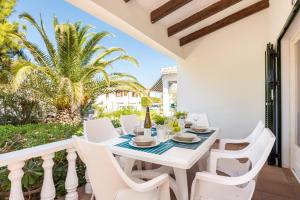 a white dining table and chairs on a balcony with palm trees at Arenal Jardí 49-4 - Arenal den Castell in Arenal d'en Castell