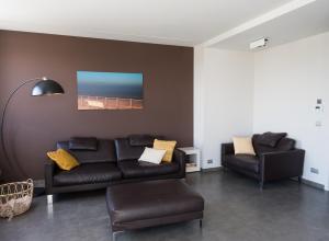 a living room with a leather couch and a chair at Camping Veld & Duin in Bredene