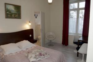 1 dormitorio con cama, escritorio y ventana en Acacias Apparts Hotel, en Plombières-les-Bains
