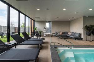 een woonkamer met een zwembad, stoelen en een bank bij Fruitpark Hotel & Spa in Ochten