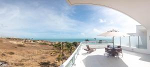 a balcony with two chairs and an umbrella and the ocean at Pousada Mar Aberto in Beberibe