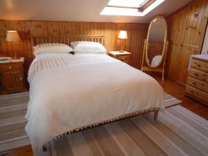 a bedroom with a large white bed and a mirror at Island View Cottage Bantry in Bantry