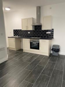 uma cozinha com armários brancos e piso em azulejo preto em Nantwich House em Crewe