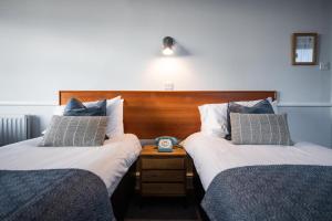 a hotel room with two beds and a clock on a night stand at The Elizabeth in Sidmouth