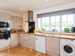 a kitchen with white cabinets and a washer and dryer at Be Our Guest Cottage in Truro