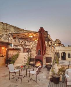 un patio con chimenea, sillas y sombrilla en Yunak Evleri Cappadocia, en Ürgüp
