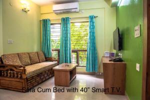 a living room with a couch and a tv at Emerald By Olys Apartment in Kolkata