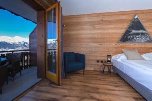 una camera da letto con un letto e una sedia sul balcone di Hôtel Chalet Royal a Veysonnaz