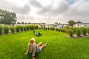 a woman sitting on the grass in a yard at Camping Veld & Duin in Bredene