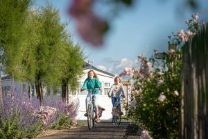2 fillettes à vélo sur un chemin fleuri dans l'établissement Camping Veld & Duin, à Bredene
