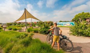 Ein kleiner Junge, der neben einem Fahrrad steht. in der Unterkunft Camping Veld & Duin in Bredene