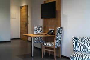 a room with a desk with two chairs and a phone at Hotel No151 in Differdange