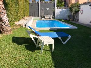 einen Pool mit einer Bank, einem Tisch und einem Stuhl in der Unterkunft Chalet Palacio Valdes in Torremolinos