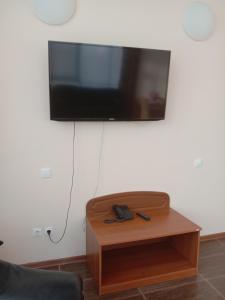 TV de pantalla plana colgada en una pared sobre una mesa de madera en Azalya Hotel, en Kazán