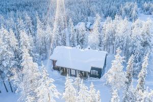 a snow covered cabin in the middle of a snow covered forest at Rentorakka in Kittilä