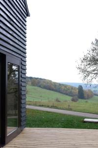 una casa con una puerta de cristal con vistas a un campo en Chalet d'Orti, en Sainte-Ode