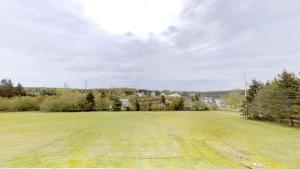 un gran campo de césped con árboles en el fondo en Bayview Pines Country Inn B&B, en Mahone Bay