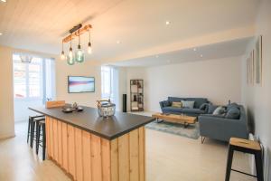 eine Küche und ein Wohnzimmer mit einer Theke und einer Couch in der Unterkunft La Maison Bleue - En plein cœur d'Arcachon in Arcachon
